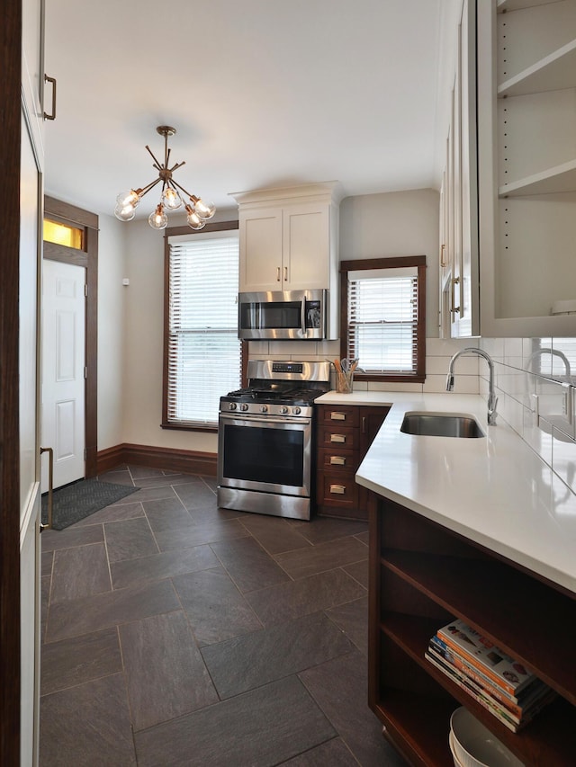 459 E Whittier St, Columbus, OH 43206 - kitchen featuring appliances with stainless steel finishes, a sink, open shelves, decorative backsplash, and a chandelier