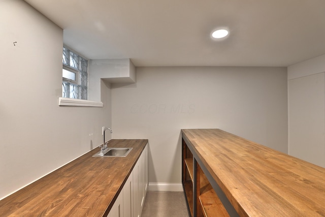 459 E Whittier St, Columbus, OH 43206 - kitchen featuring butcher block countertops, a sink, white cabinetry, and baseboards