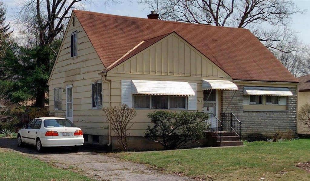 bungalow with a chimney, a front lawn, board and batten siding, and a shingled roof