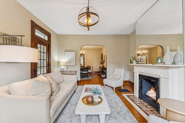 1057 Harrison Ave, Columbus, OH 43201 - living room with a chandelier, arched walkways, wood finished floors, and a fireplace with flush hearth