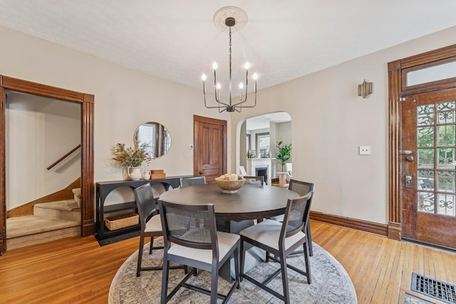 1057 Harrison Ave, Columbus, OH 43201 - dining room with arched walkways, light wood-style floors, stairway, and a chandelier