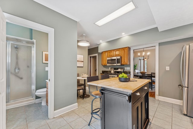 1057 Harrison Ave, Columbus, OH 43201 - kitchen featuring appliances with stainless steel finishes, wood counters, light tile patterned flooring, a breakfast bar, and ornamental molding