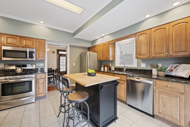 1057 Harrison Ave, Columbus, OH 43201 - kitchen with appliances with stainless steel finishes, light tile patterned floors, a breakfast bar, wood counters, and recessed lighting