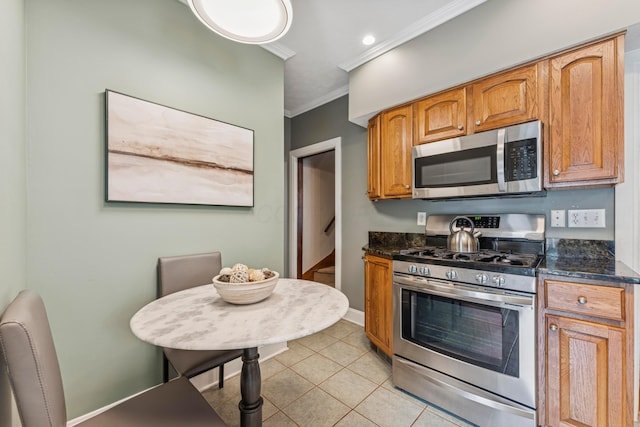 1057 Harrison Ave, Columbus, OH 43201 - kitchen with stainless steel appliances, ornamental molding, light tile patterned flooring, brown cabinetry, and dark stone countertops