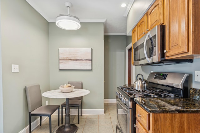 1057 Harrison Ave, Columbus, OH 43201 - kitchen featuring appliances with stainless steel finishes, crown molding, brown cabinetry, dark stone counters, and light tile patterned floors