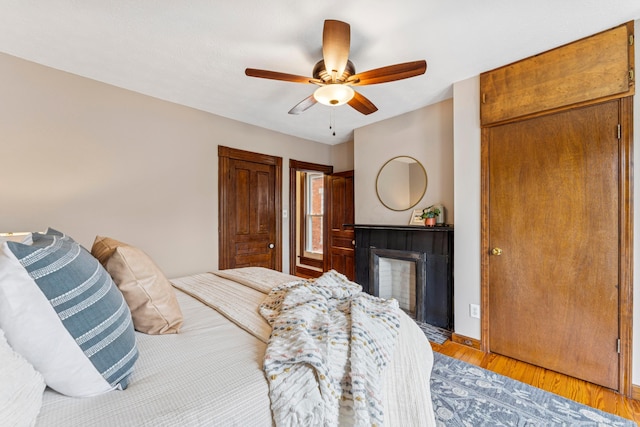 1057 Harrison Ave, Columbus, OH 43201 - bedroom featuring a fireplace with flush hearth, light wood-type flooring, and ceiling fan