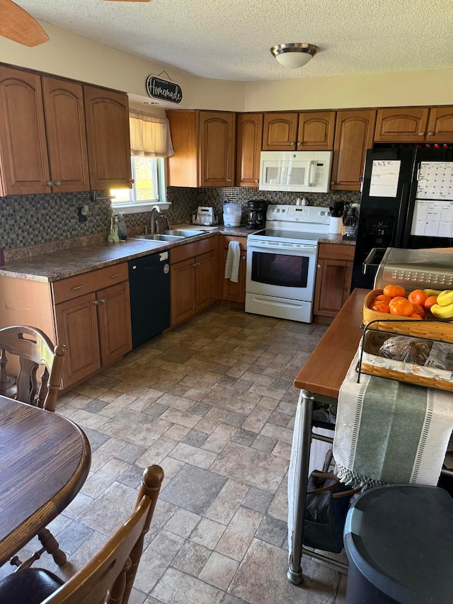 kitchen featuring black appliances, decorative backsplash, brown cabinetry, a textured ceiling, and a sink