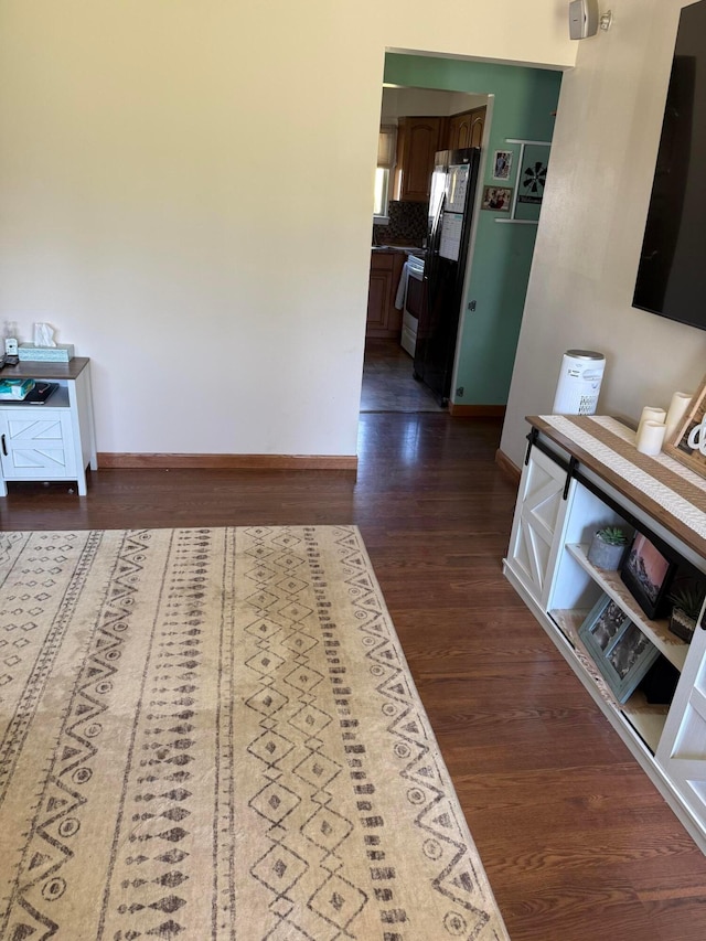 hallway featuring dark wood-style flooring and baseboards