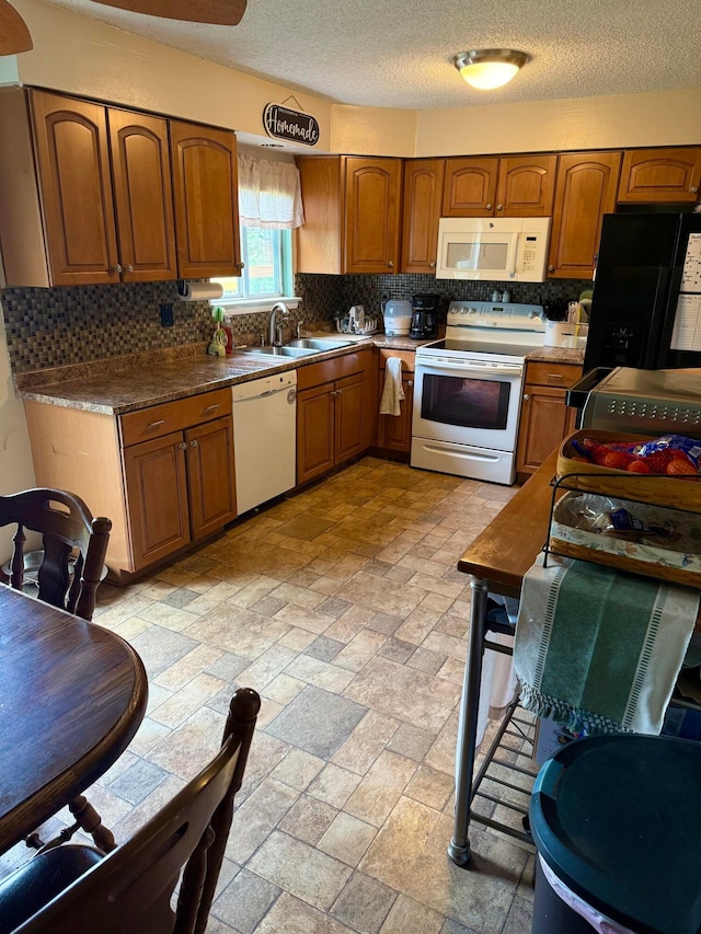 kitchen featuring white appliances, decorative backsplash, a sink, brown cabinets, and a textured ceiling