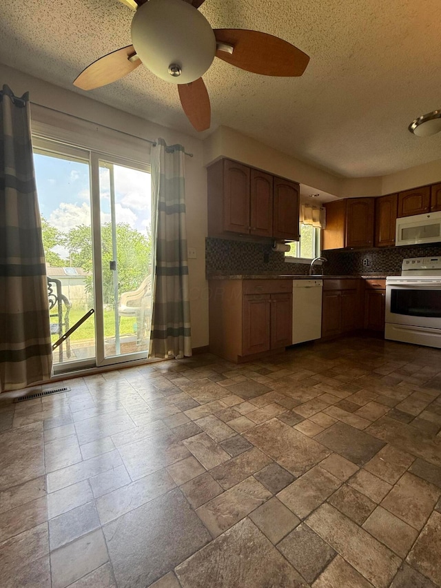 2836 Palisades Ave, Columbus, OH 43207 - kitchen with white appliances, tasteful backsplash, ceiling fan, a textured ceiling, and stone tile flooring