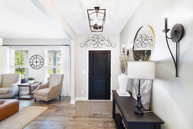entryway featuring wood finished floors, baseboards, and a chandelier