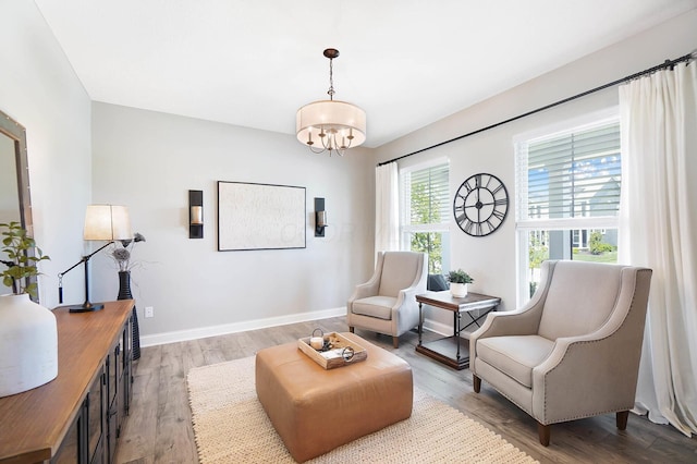 sitting room featuring a chandelier, light wood-style flooring, and baseboards