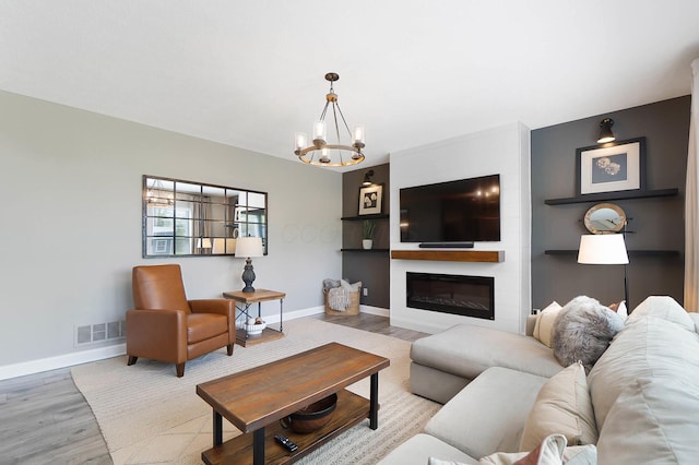 living room with wood finished floors, baseboards, a chandelier, and a fireplace