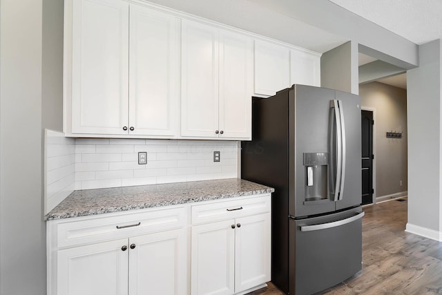 kitchen with stainless steel refrigerator with ice dispenser, backsplash, white cabinetry, and wood finished floors
