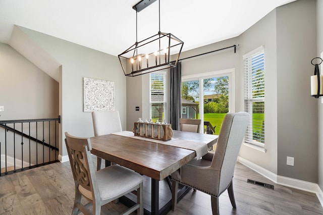 dining space featuring wood finished floors, baseboards, and a chandelier