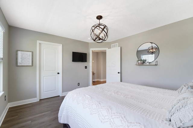 bedroom featuring dark wood-type flooring, a chandelier, baseboards, and multiple windows