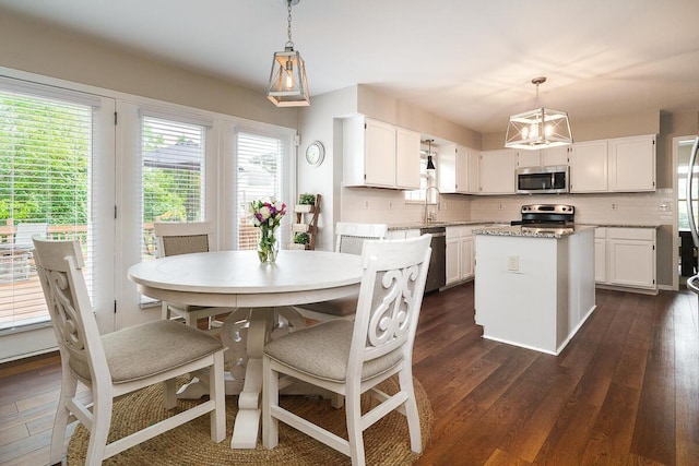 kitchen with stainless steel appliances, dark wood-type flooring, a center island, white cabinetry, and a sink