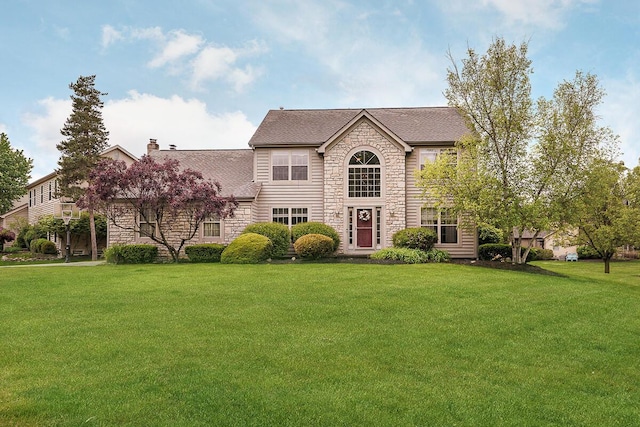 view of front of house with stone siding, a front lawn, a chimney, and a shingled roof