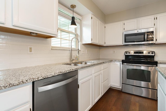 kitchen with stainless steel appliances, a sink, dark wood-style floors, white cabinets, and tasteful backsplash