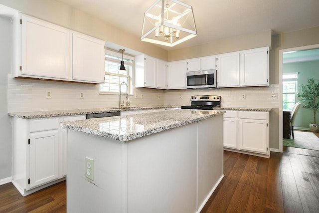 kitchen with appliances with stainless steel finishes, a sink, plenty of natural light, and white cabinetry