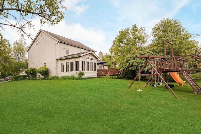 view of green lawn with a playground and a deck