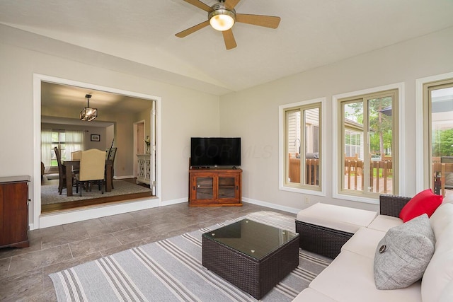 living area with a ceiling fan, vaulted ceiling, and baseboards