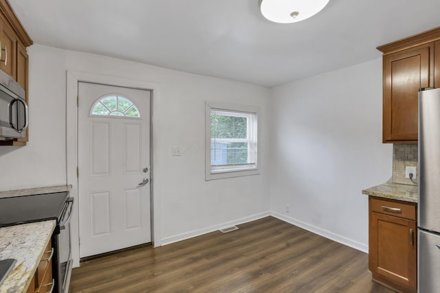 155 N Harris Ave, Columbus, OH 43204 - kitchen with stainless steel appliances, dark wood-type flooring, light stone countertops, brown cabinets, and baseboards