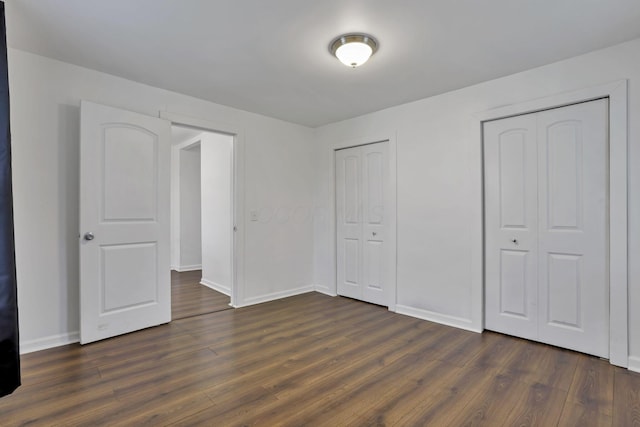 155 N Harris Ave, Columbus, OH 43204 - unfurnished bedroom with dark wood-style flooring, baseboards, and multiple closets