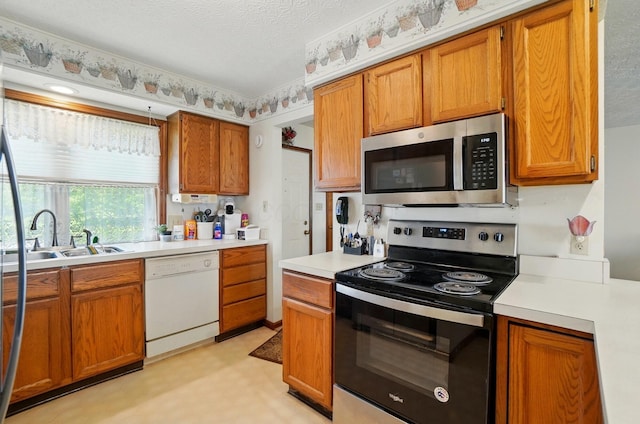371 Federal Cir, Delaware, OH 43015 - kitchen with appliances with stainless steel finishes, light countertops, brown cabinetry, a sink, and a textured ceiling