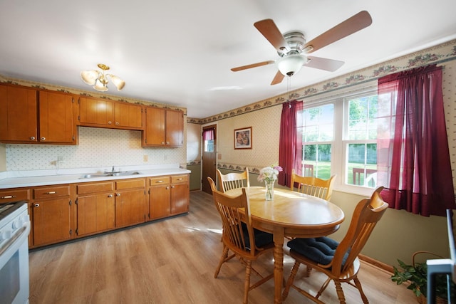 6082 Bolamo Ct, Westerville, OH 43081 - kitchen with a sink, brown cabinets, wallpapered walls, white range with gas cooktop, and light countertops