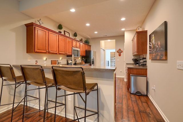 4115 Aumbrey Ct, New Albany, OH 43054 - kitchen with appliances with stainless steel finishes, a peninsula, dark wood-style floors, recessed lighting, and brown cabinetry