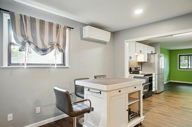 820 N Walnut St, Baltimore, OH 43105 - kitchen featuring stainless steel appliances, a wall mounted air conditioner, baseboards, dark wood-style flooring, and white cabinets