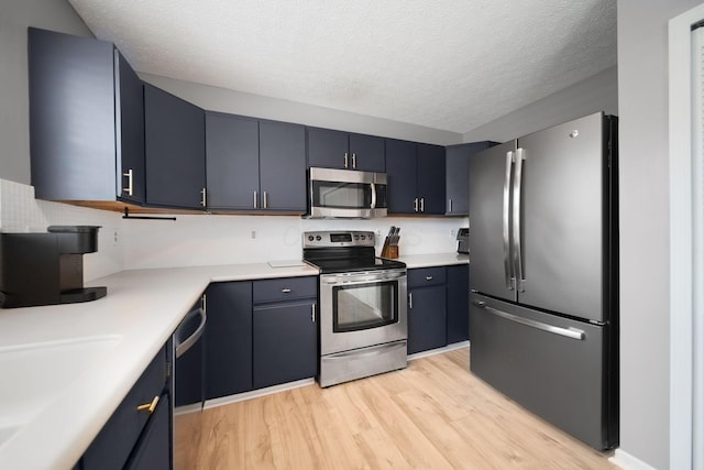 kitchen featuring appliances with stainless steel finishes, light wood-style flooring, light countertops, and a textured ceiling