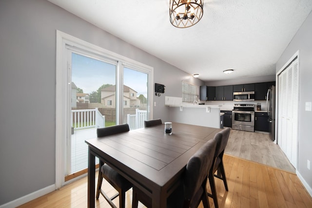 dining space featuring light wood-type flooring, baseboards, and a chandelier