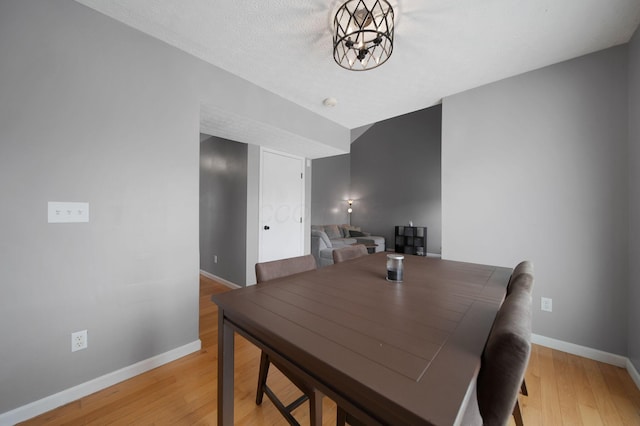 dining room featuring baseboards, light wood-style flooring, and a chandelier