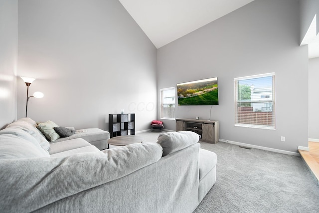 living area with high vaulted ceiling, plenty of natural light, carpet, and baseboards