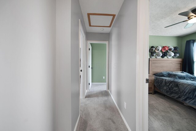 corridor with carpet, a textured ceiling, and baseboards