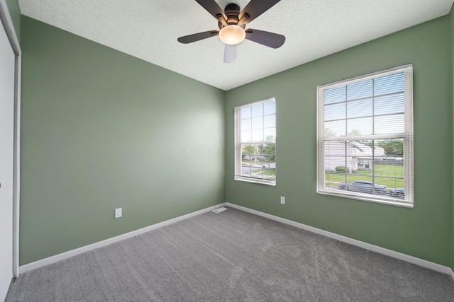 empty room with baseboards, carpet flooring, ceiling fan, and a textured ceiling