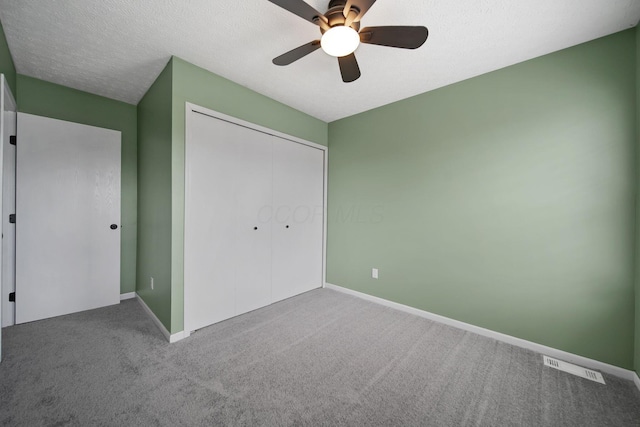 unfurnished bedroom with carpet flooring, a closet, baseboards, and a ceiling fan