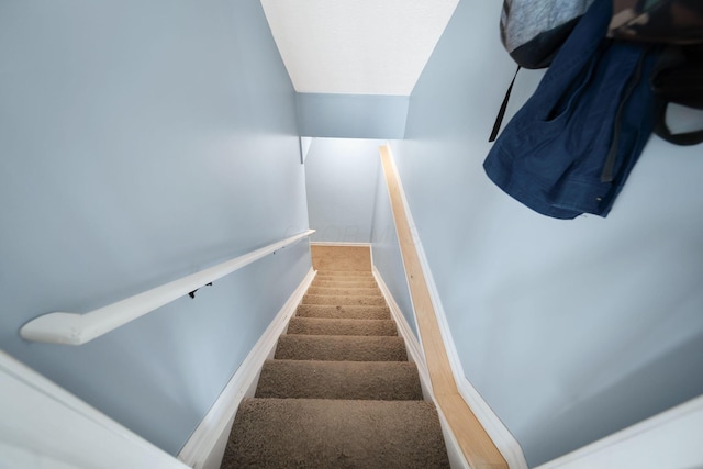stairway featuring carpet floors, baseboards, and lofted ceiling