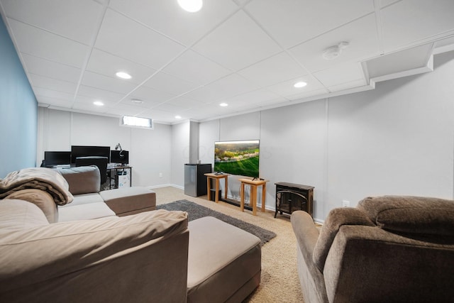 carpeted living room featuring recessed lighting, a paneled ceiling, a wood stove, baseboards, and a desk