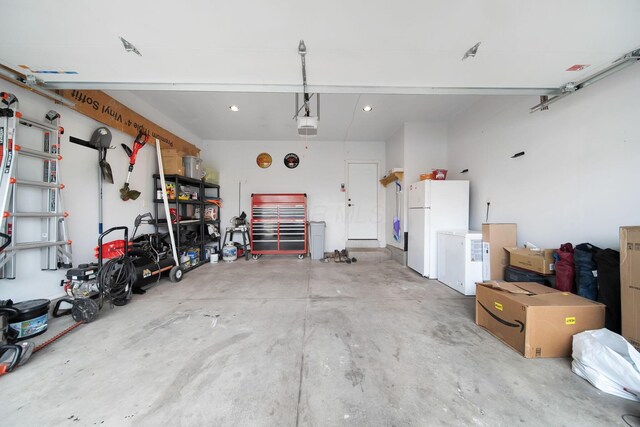 garage with freestanding refrigerator, a garage door opener, and recessed lighting