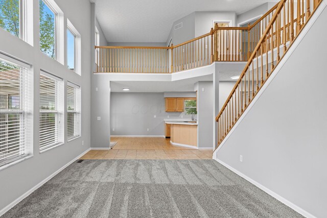 1980 Maxwell Ave, Lewis Center, OH 43035 - unfurnished living room featuring a high ceiling, light carpet, stairway, baseboards, and light tile patterned flooring