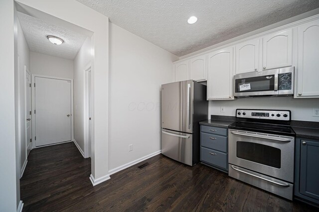 1019 Wallace Dr, Delaware, OH 43015 - kitchen with appliances with stainless steel finishes, a textured ceiling, dark countertops, dark wood-style floors, and white cabinets