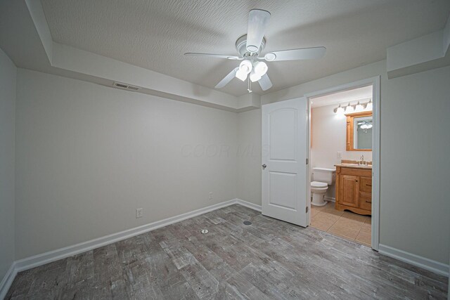 1019 Wallace Dr, Delaware, OH 43015 - unfurnished bedroom with wood finished floors, a sink, baseboards, ensuite bath, and a ceiling fan