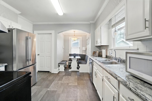 114 Roosevelt Dr, Springfield, OH 45504 - kitchen with a sink, stainless steel appliances, arched walkways, decorative backsplash, and white cabinetry
