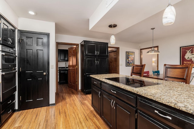 5754 N Loch Maree Ct N, Dublin, OH 43017 - kitchen with black appliances, light wood-style floors, decorative light fixtures, light stone countertops, and dark cabinets