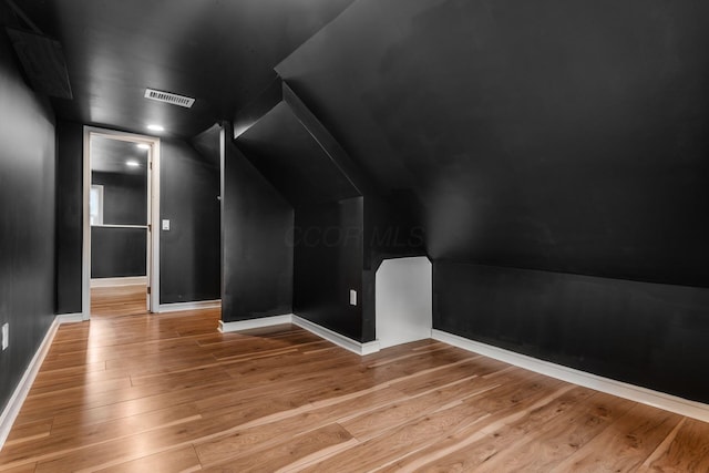bonus room with light wood-style floors, lofted ceiling, and baseboards