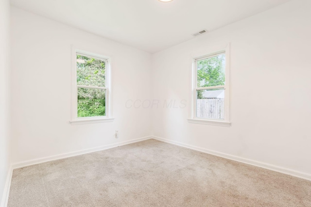 unfurnished room with plenty of natural light, carpet, and baseboards
