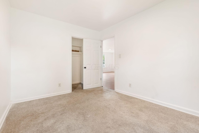 spare room featuring light colored carpet and baseboards